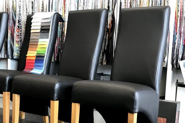 Three black vinyl dining chairs in a row